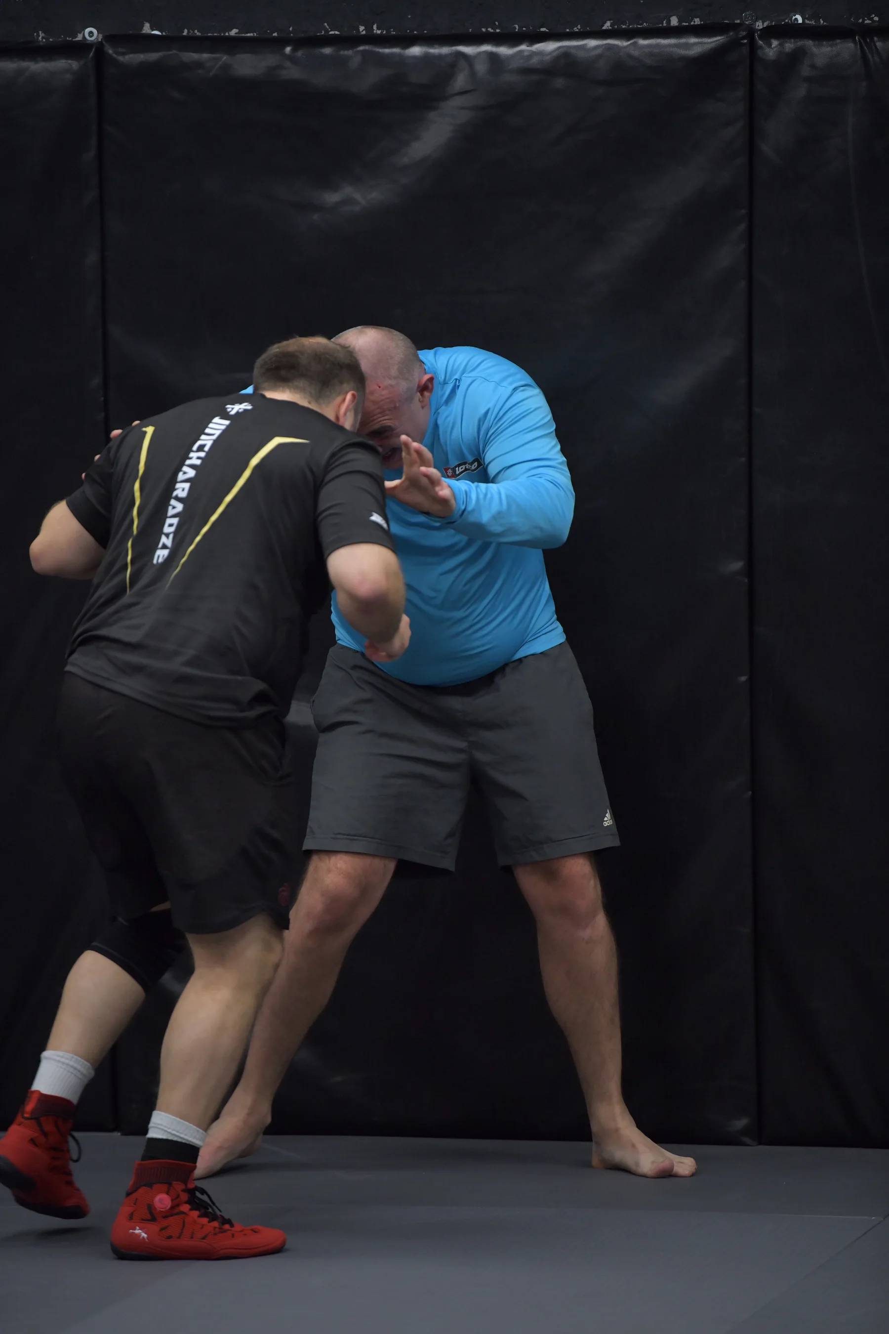 Adult wrestlers drilling hand fighting against the wall mats